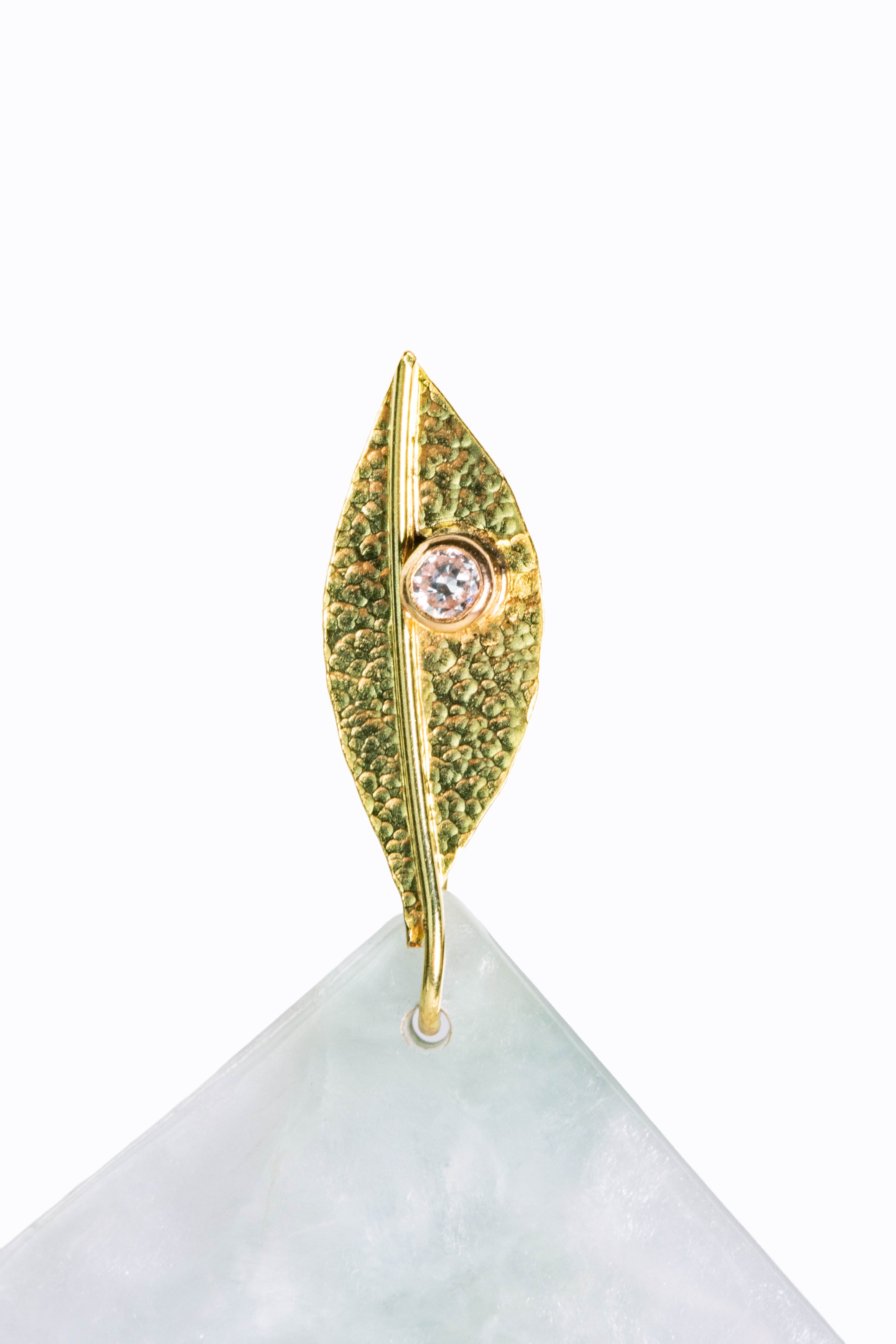 Close-up detail of Cirrus earring 18k hammered gold leaf stud with bezel-set diamond and Burmese jade fan by Alexandra Essex