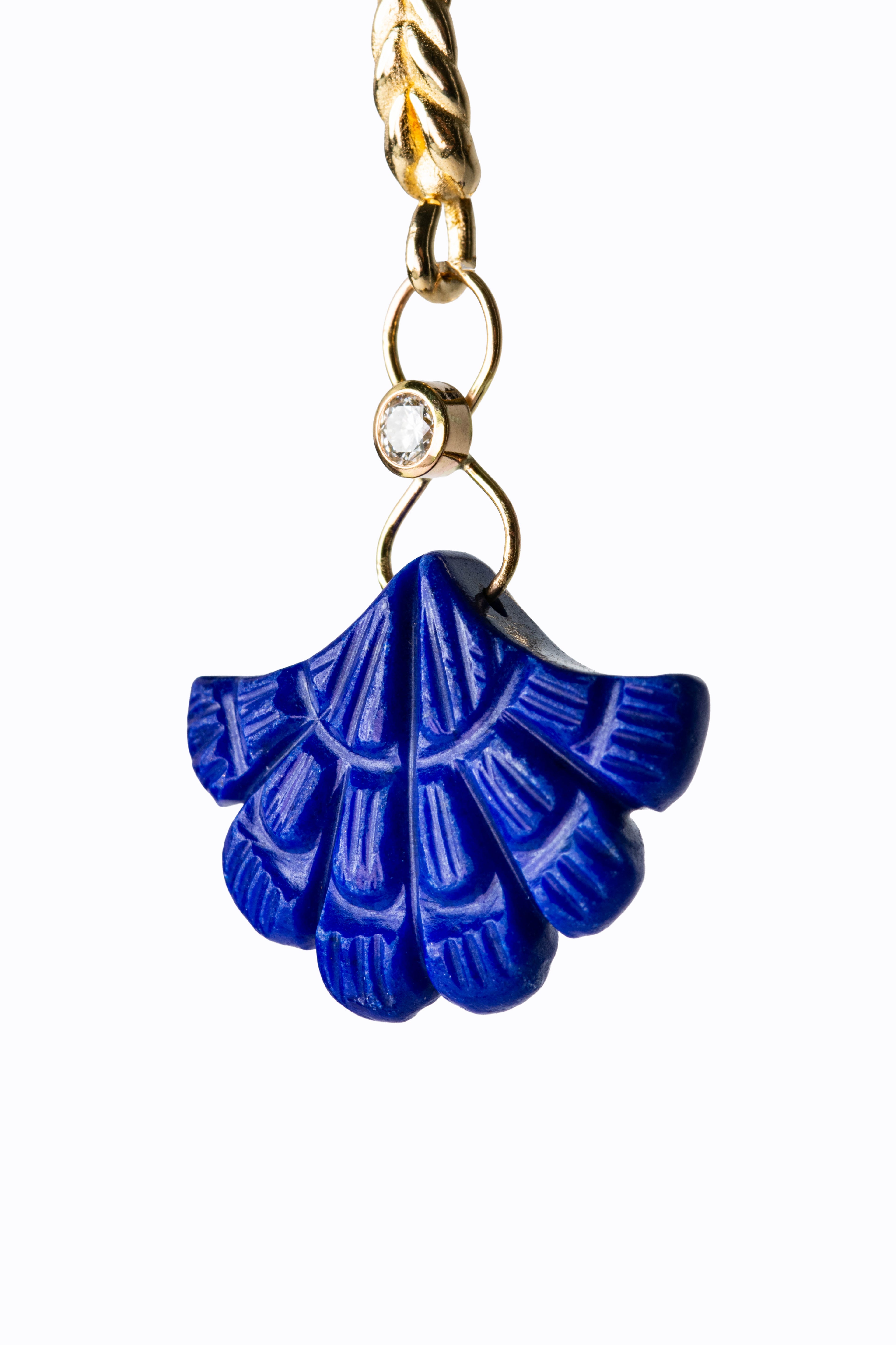 Close-up of Abanico carved lapis lazuli fan earring showing deep blue stone carving detail with bezel-set diamond and 14k gold link by Alexandra Essex