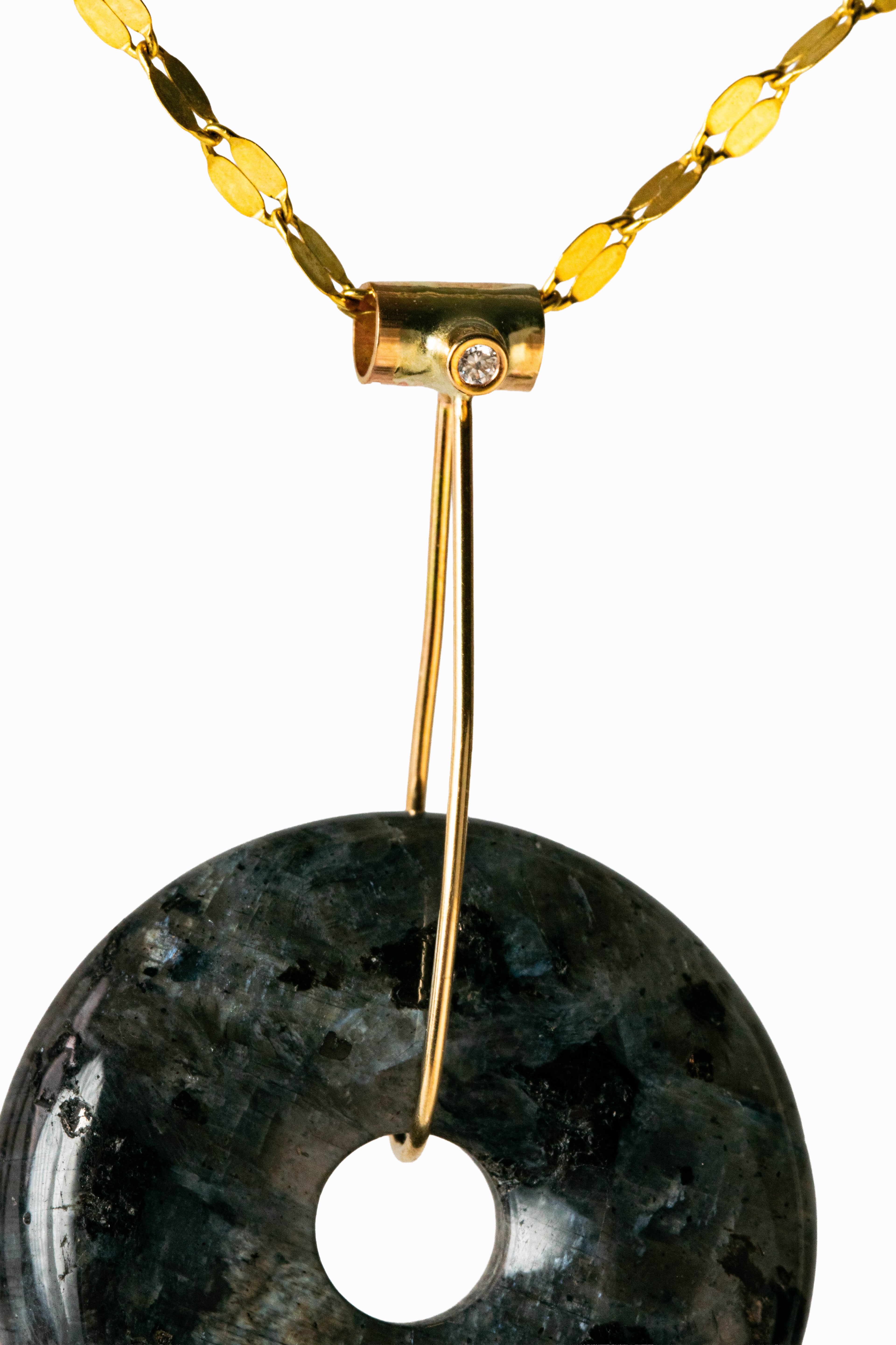 Larvikite disc pendant close-up showing dark feldspar with silver-blue schiller and 14k gold diamond bail by Alexandra Essex