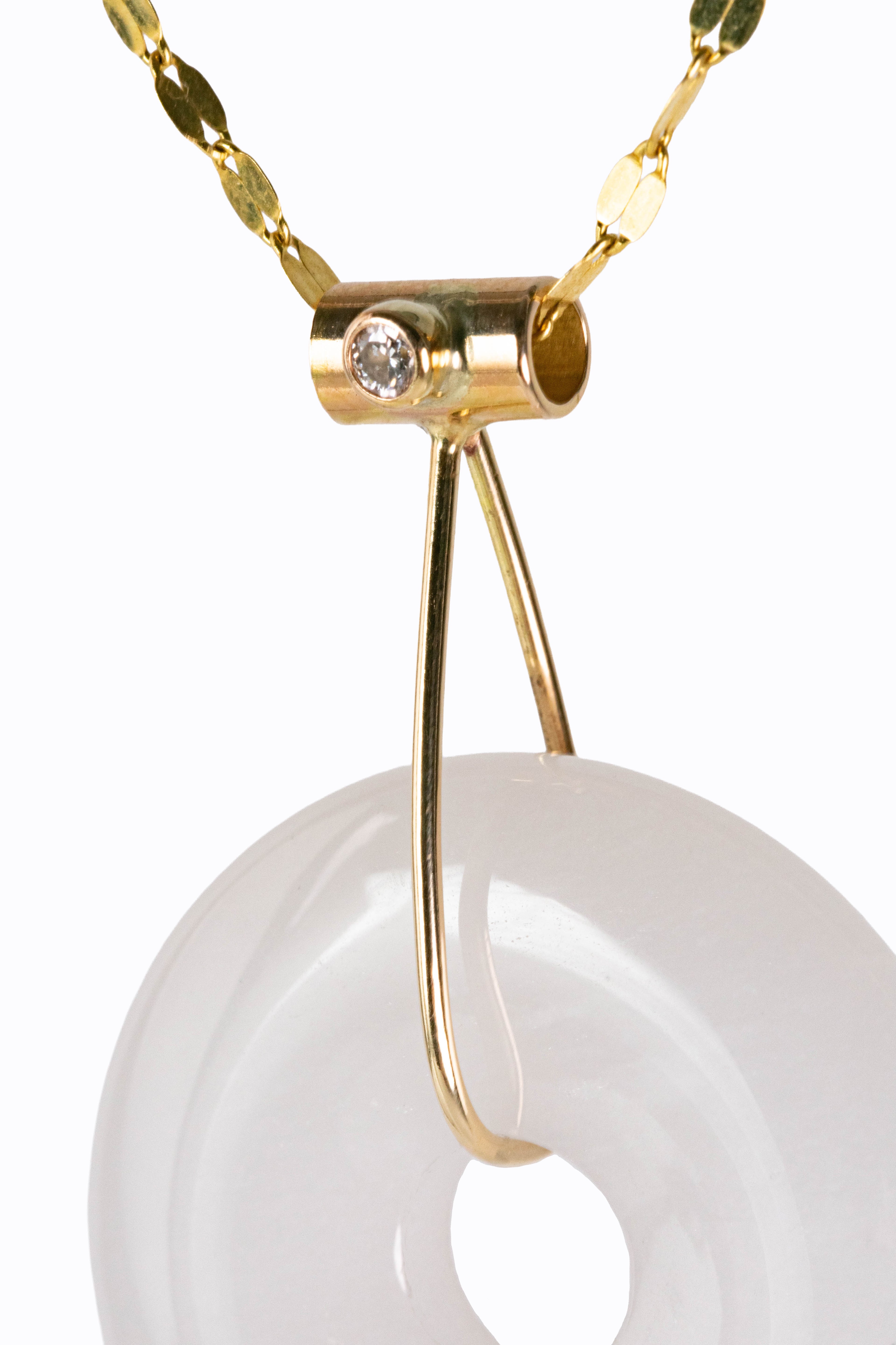 Close-up detail of La Lune pendant bezel-set diamond accent and 14k gold bail on white marble disc by Alexandra Essex